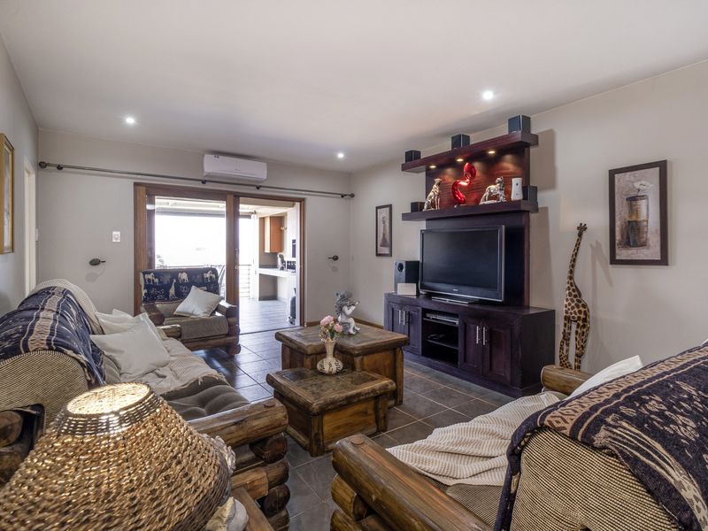A comfortable living room featuring tiled flooring, a built-in media unit, recessed lighting, and a split-system air conditioner, with access to an outdoor patio area.