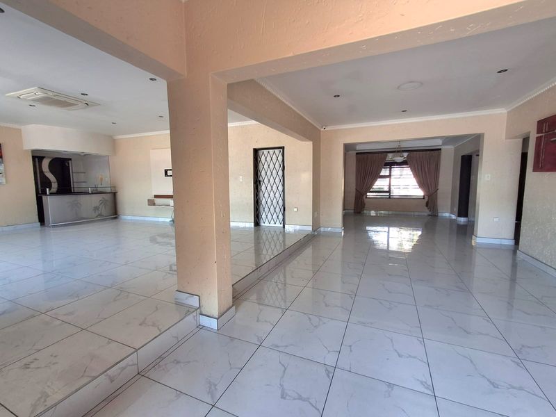 Spacious open-plan living area featuring polished marble-look porcelain tiles, recessed lighting, and a built-in bar, offering a versatile layout for modern living.