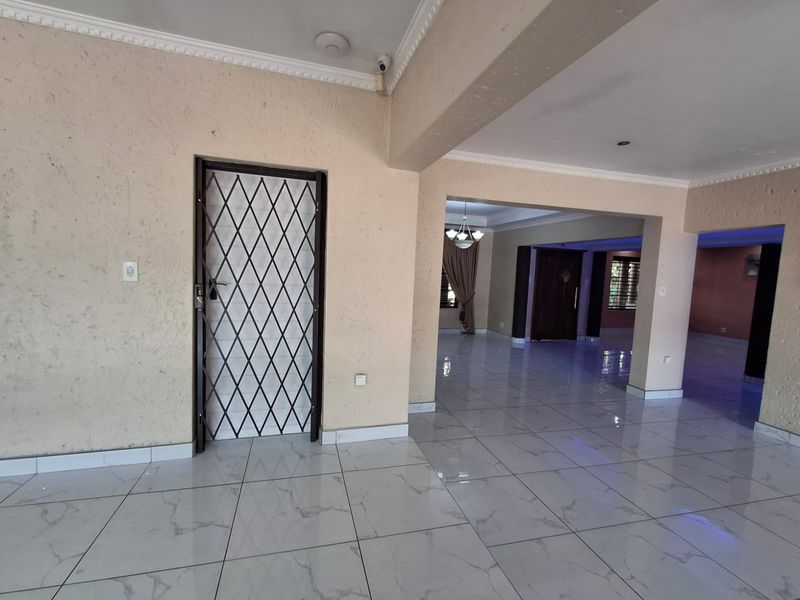 Spacious open-plan living area featuring polished porcelain floor tiles, decorative crown molding, and a secure metal entrance gate.