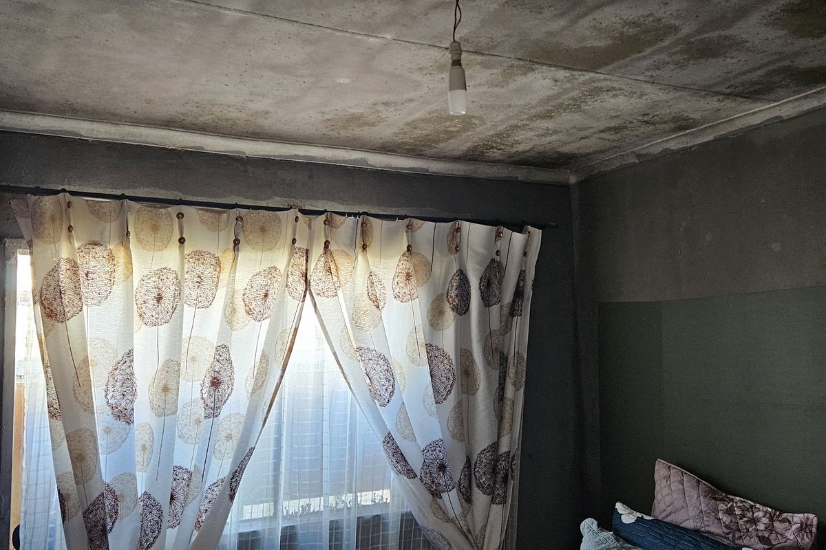 Bedroom interior showing significant ceiling water damage and staining, requiring urgent maintenance and repair to the ceiling and wall finishes.