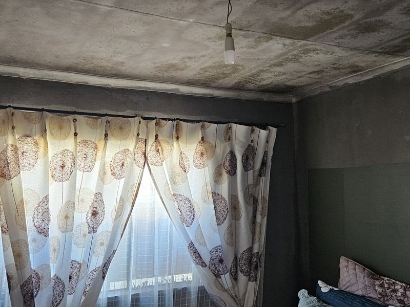 Bedroom interior showing significant ceiling water damage and staining, requiring urgent maintenance and repair to the ceiling and wall finishes.