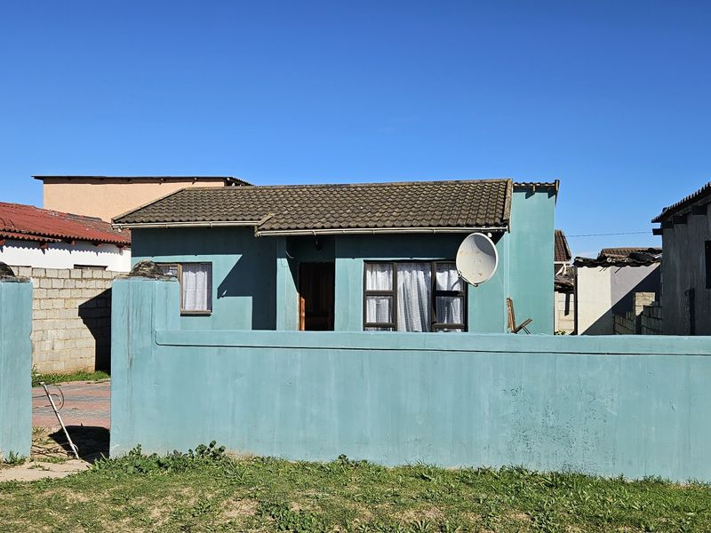 Front view of a single-story residential property featuring a boundary wall, tiled roof, and exterior solar water heating system.