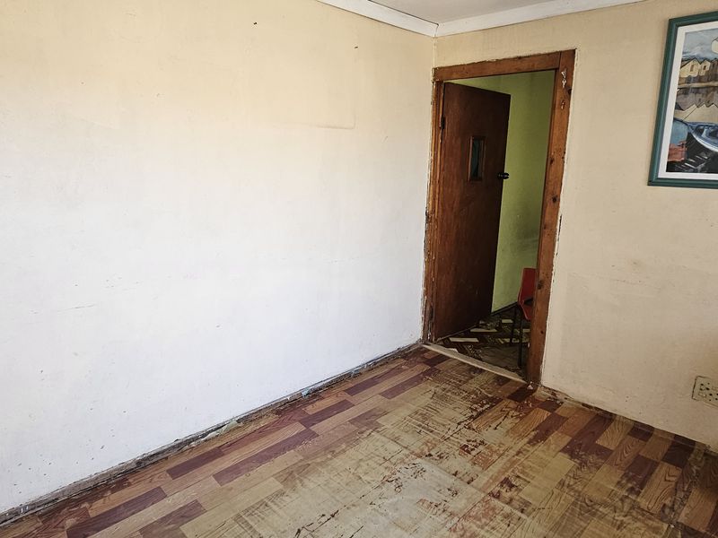 An empty bedroom space featuring worn flooring and plain walls, requiring cosmetic updates and new flooring to improve its overall condition.