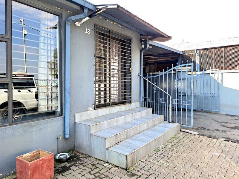 Front entrance featuring tiled steps, security gate, and metal perimeter fencing, providing access to the main dwelling.