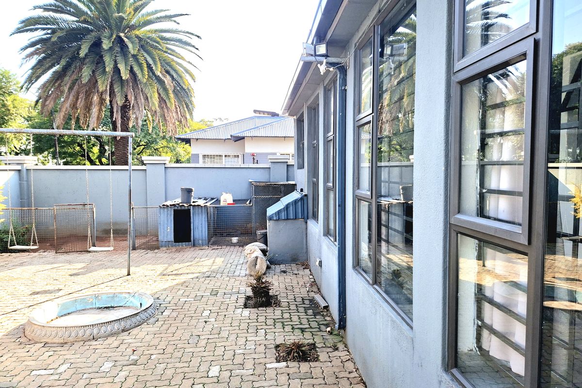 Rear exterior area featuring paved patio, perimeter wall, and aluminium window frames, offering a functional outdoor space with potential for landscaping improvements.
