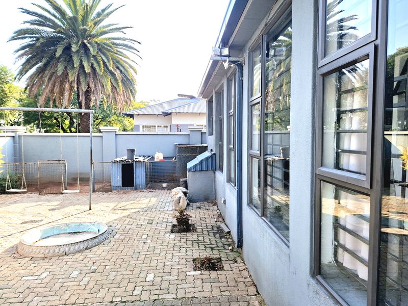 Rear exterior area featuring paved patio, perimeter wall, and aluminium window frames, offering a functional outdoor space with potential for landscaping improvements.