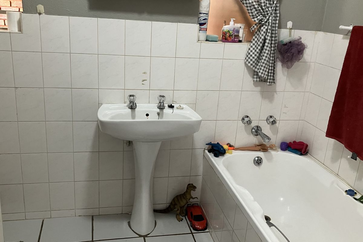 A functional bathroom featuring a pedestal basin and a standard bathtub with white wall and floor tiling.