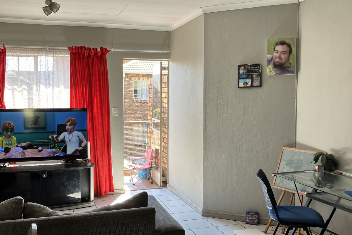 A living room featuring tiled flooring, coved ceilings, and a sliding door providing access to an outdoor balcony area.