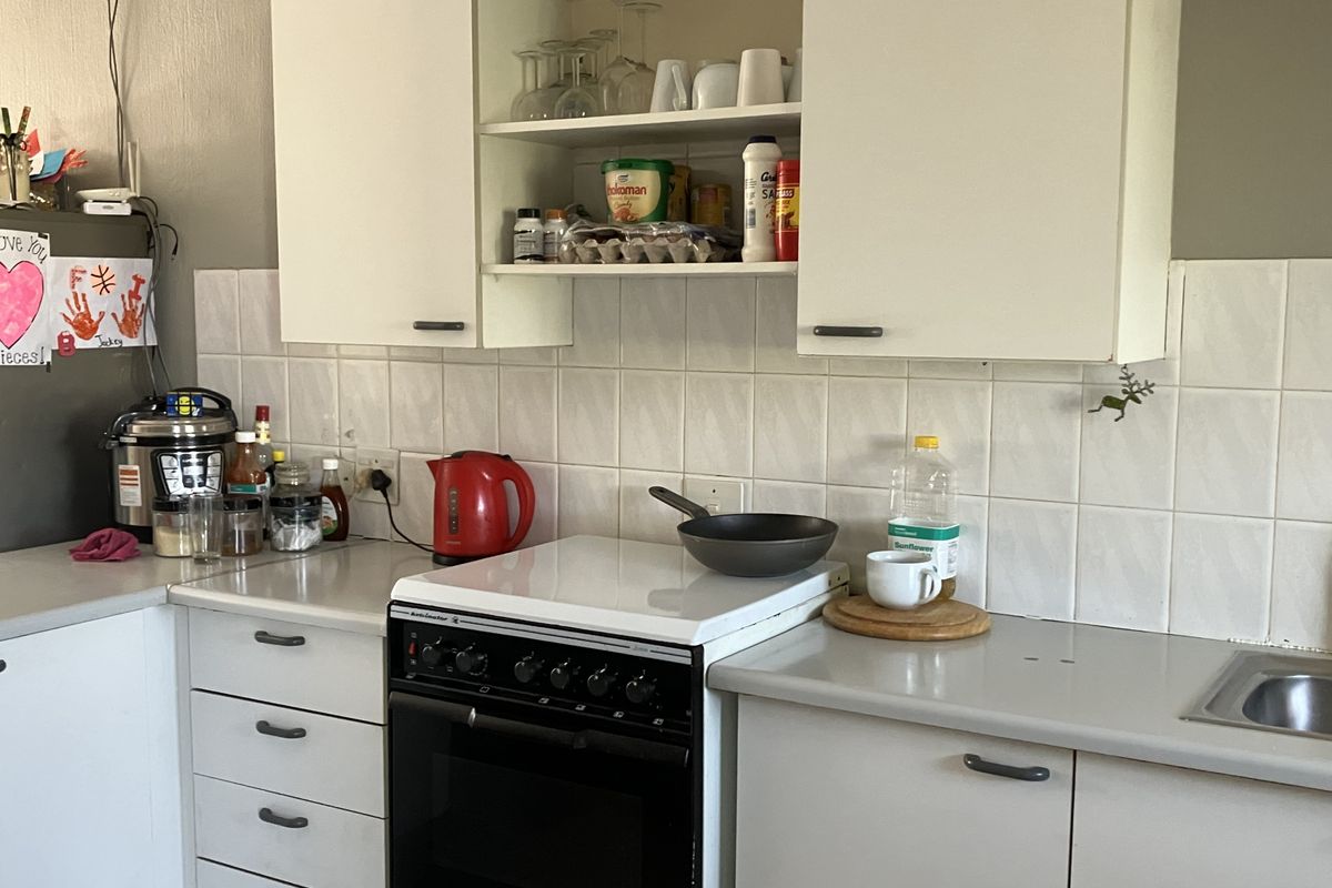 A functional kitchen featuring white cabinetry, tiled backsplash, laminate countertops, and a freestanding stove, providing a practical workspace for daily cooking.