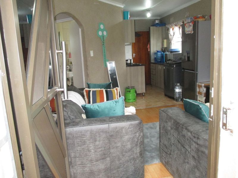 Open-plan living area featuring a combined kitchen with built-in cabinetry and a lounge space with mixed flooring finishes.
