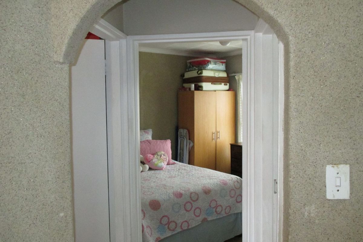 A view through an arched doorway into a bedroom featuring textured wall finishes and standard interior door frame.
