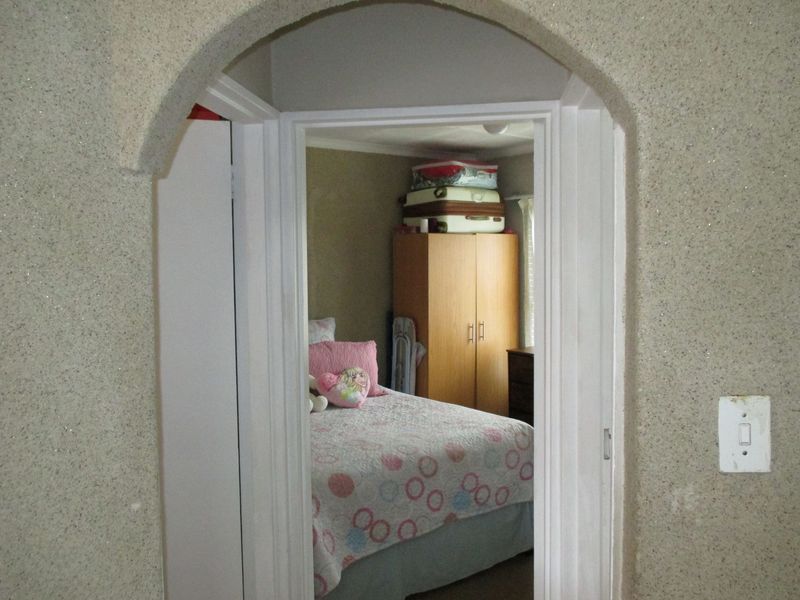 A view through an arched doorway into a bedroom featuring textured wall finishes and standard interior door frame.