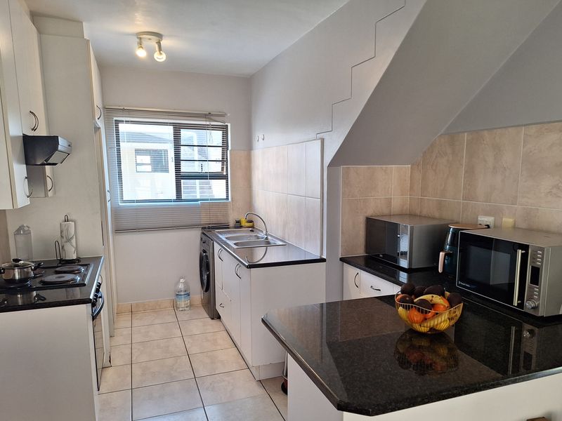 A functional kitchen featuring granite countertops, tiled backsplash, built-in cabinetry, and integrated appliances, offering a clean and practical workspace.