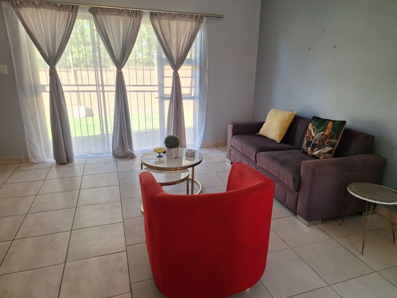 A living room featuring neutral tiled flooring and a large sliding glass door that provides access to the outdoor area.