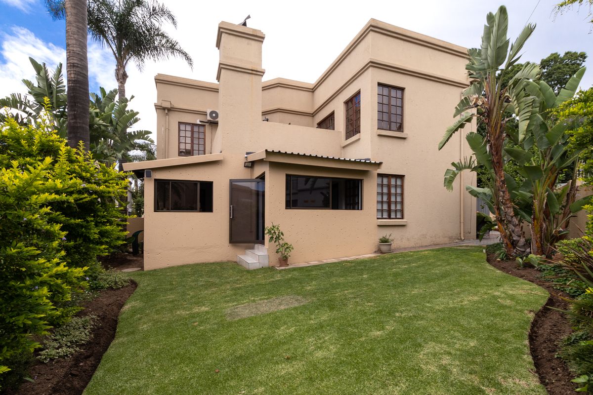 Rear view of the duet property featuring a plastered facade, prominent chimney, timber-framed windows, and a well-maintained garden area.