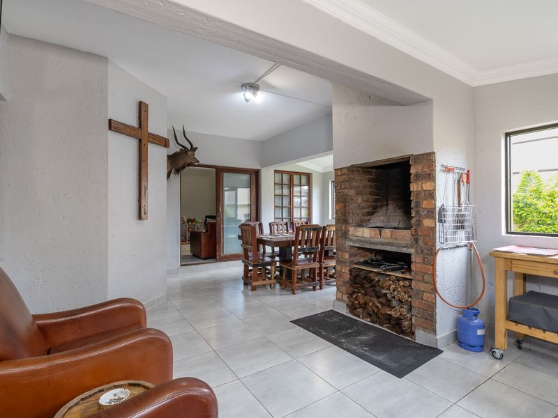 Spacious living area featuring a built-in brick fireplace, tiled flooring, and direct access to the dining space through sliding glass doors.