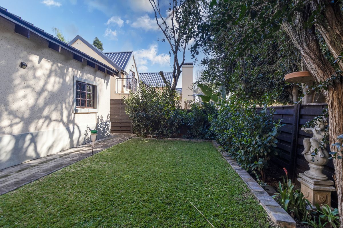 A well-maintained rear garden featuring a manicured lawn, paved walkway, and established perimeter fencing, providing a private outdoor space for the townhouse.
