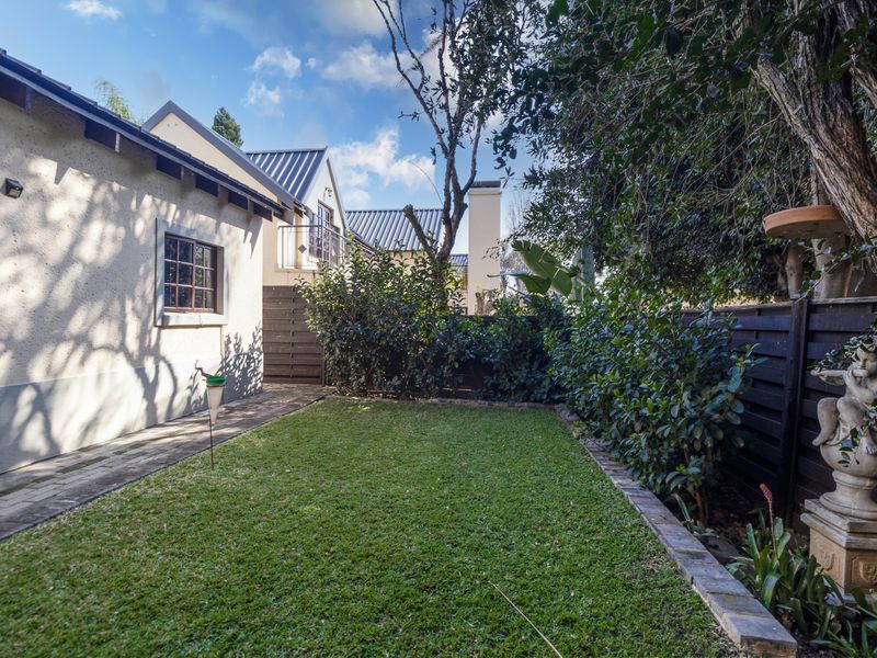 A well-maintained rear garden featuring a manicured lawn, paved walkway, and established perimeter fencing, providing a private outdoor space for the townhouse.