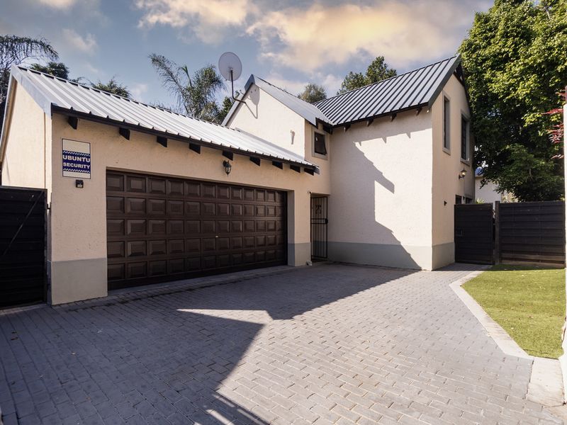 Front elevation of a townhouse featuring a double garage, paved driveway, and well-maintained exterior finishes.