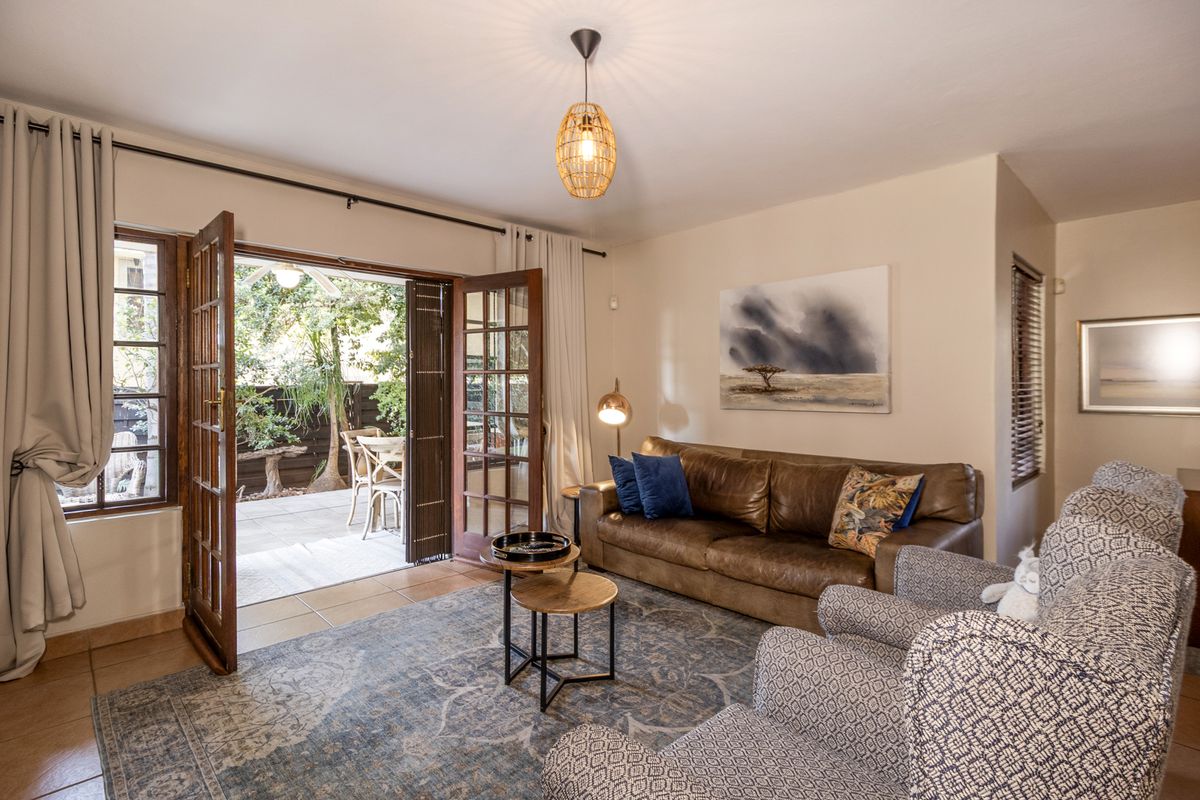 A comfortable living room featuring tiled floors and classic french doors that open directly onto a private patio area.