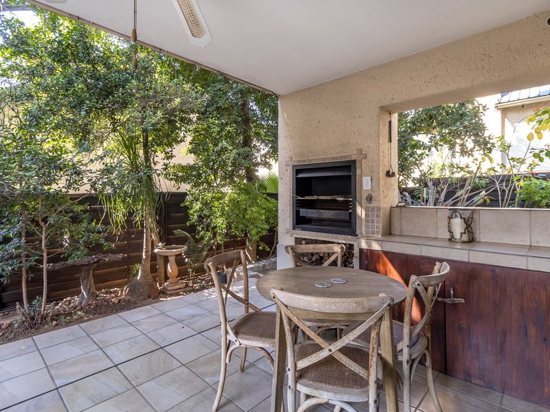 Covered patio area featuring a built-in braai, tiled flooring, and integrated cabinetry, perfect for outdoor entertaining.