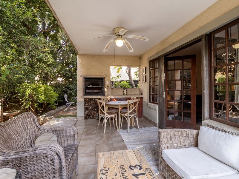 A covered patio area featuring a built-in braai, tiled flooring, and a ceiling fan, providing a comfortable outdoor entertainment space.