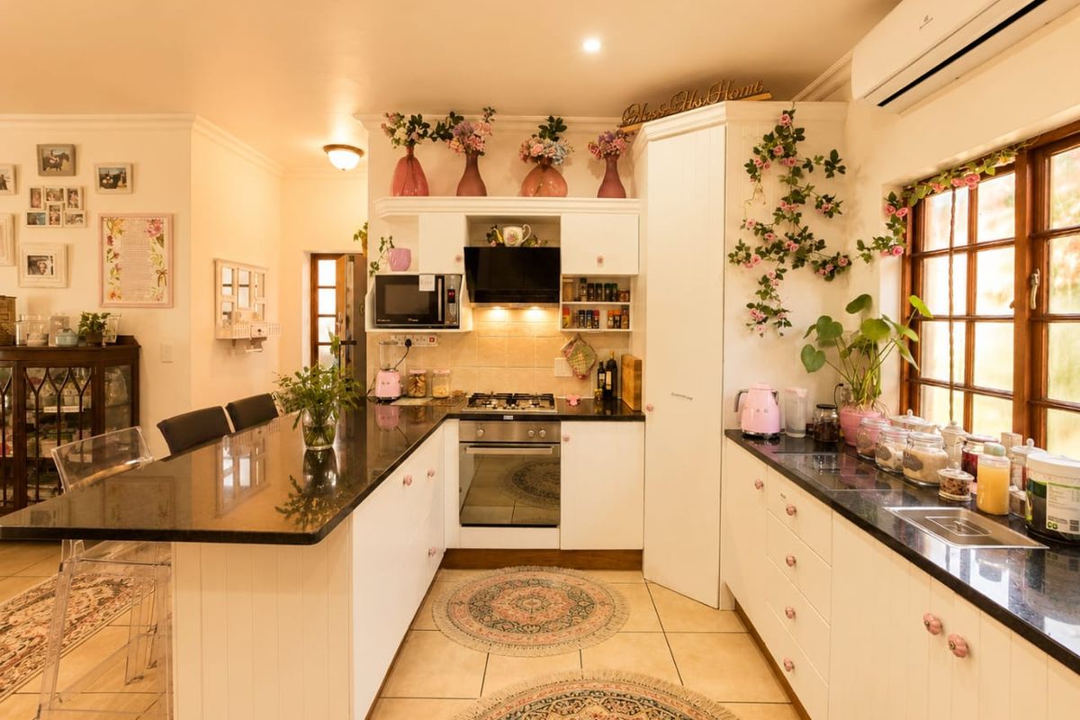 A well-maintained kitchen featuring white cabinetry, granite countertops, built-in oven, gas hob, and an integrated air conditioning unit.