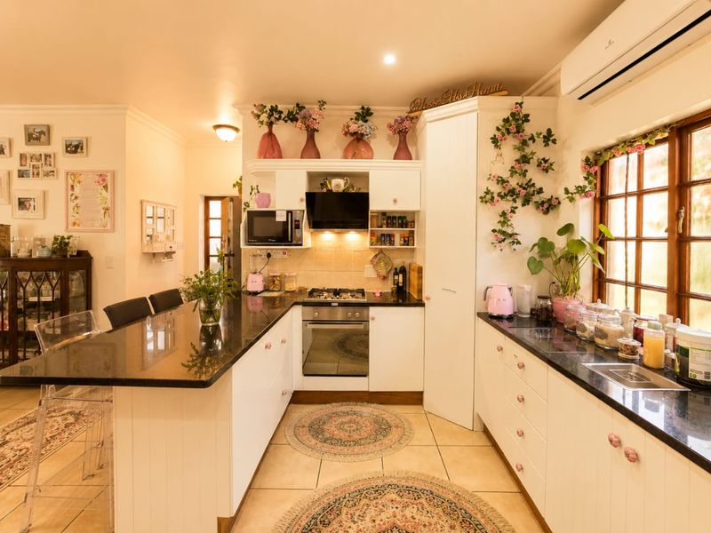 A well-maintained kitchen featuring white cabinetry, granite countertops, built-in oven, gas hob, and an integrated air conditioning unit.
