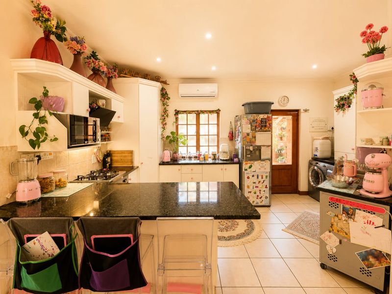 A well-appointed kitchen featuring granite countertops, built-in cabinetry, a gas hob, and tiled flooring, with direct access to an outdoor area.