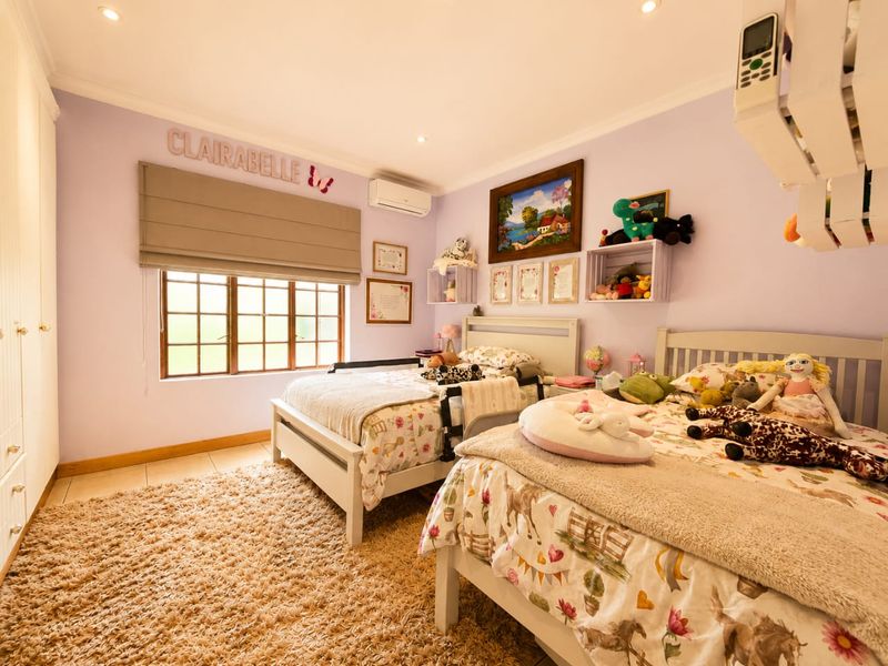 A well-maintained bedroom featuring built-in cupboards, tiled flooring, recessed lighting, and a wall-mounted air conditioning unit.