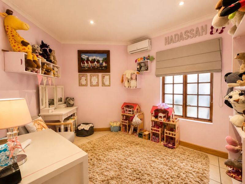A well-maintained bedroom featuring tiled flooring, recessed downlighting, an integrated air conditioning unit, and a timber-framed window with a fitted roman blind.