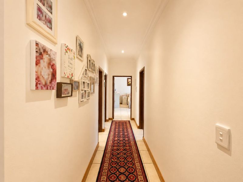 A well-maintained interior hallway featuring neutral walls, tiled flooring, and recessed downlighting, providing access to adjacent rooms.