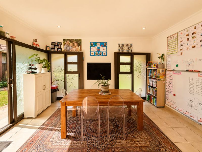 A bright living area featuring large sliding glass doors providing natural light, tiled flooring, and recessed downlights, creating a functional and inviting space.