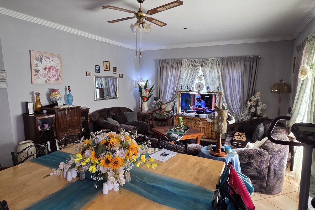 A spacious living room featuring tiled flooring, a ceiling fan, and decorative cornice detailing, providing a comfortable and functional family living area.