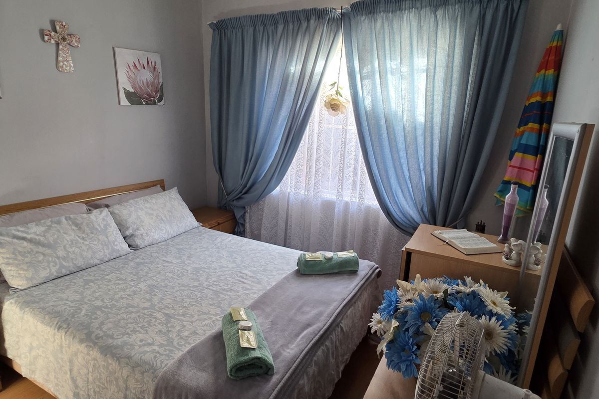 A cozy bedroom featuring neutral wall finishes and a window dressed with curtains, providing a comfortable and functional sleeping space.