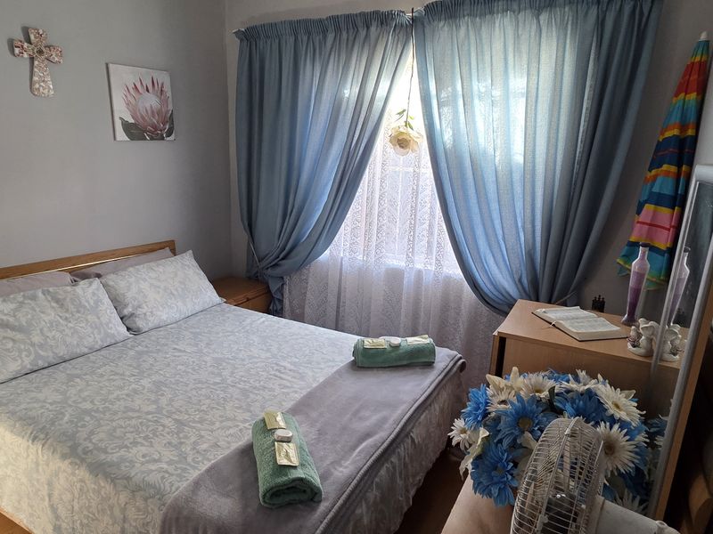 A cozy bedroom featuring neutral wall finishes and a window dressed with curtains, providing a comfortable and functional sleeping space.