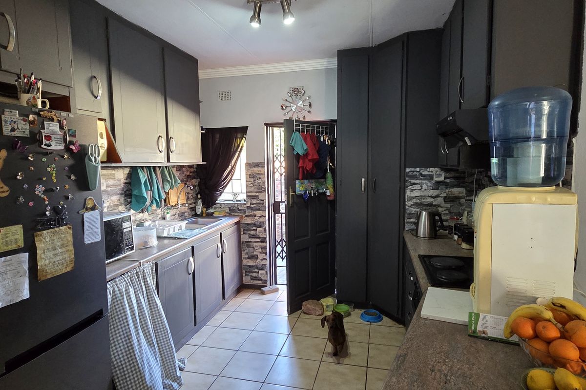A functional kitchen featuring dark cabinetry, laminate countertops, and ceramic tile flooring with direct access to the exterior.