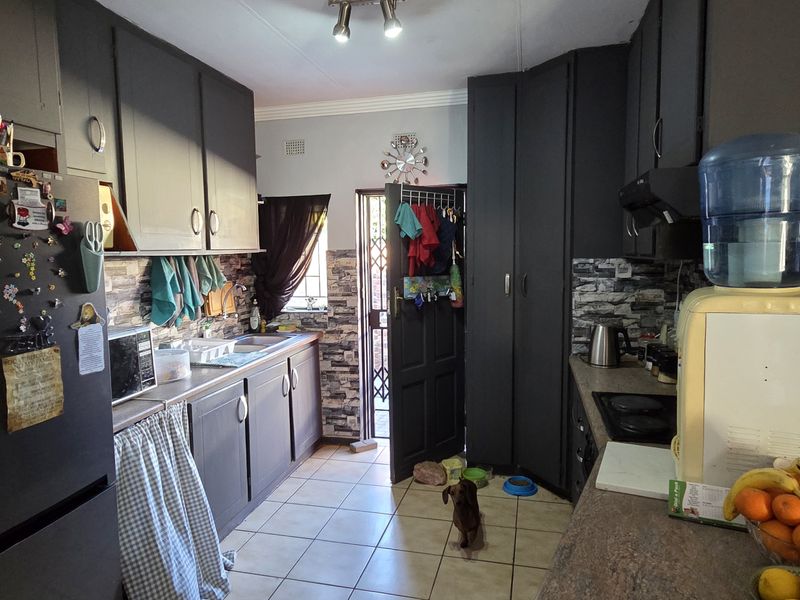 A functional kitchen featuring dark cabinetry, laminate countertops, and ceramic tile flooring with direct access to the exterior.