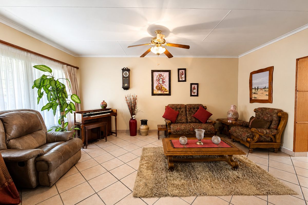A spacious living room featuring neutral tiled flooring, a central ceiling fan, and coved ceiling detailing.