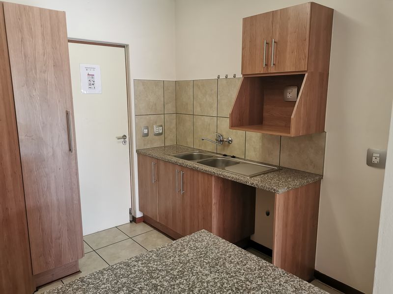 A clean, functional kitchen area featuring laminate cabinetry, granite countertops, a double stainless steel sink, and neutral tiled backsplash.