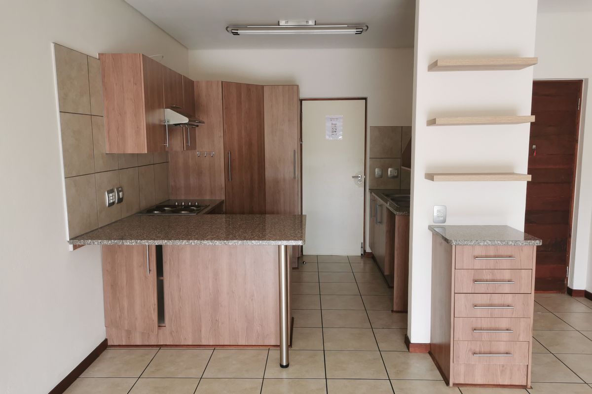A clean, functional kitchen featuring laminate cabinetry, granite countertops, a gas hob with extractor, and tiled flooring, offering a practical layout for daily use.