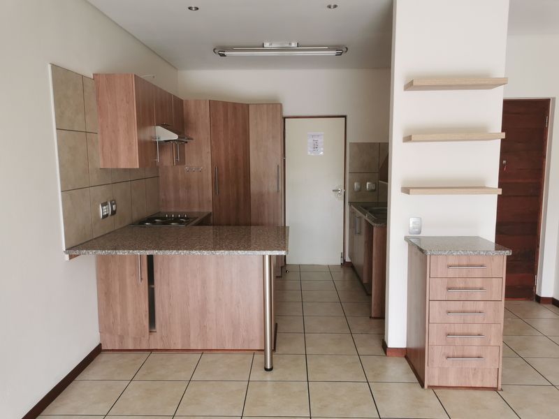 A clean, functional kitchen featuring laminate cabinetry, granite countertops, a gas hob with extractor, and tiled flooring, offering a practical layout for daily use.