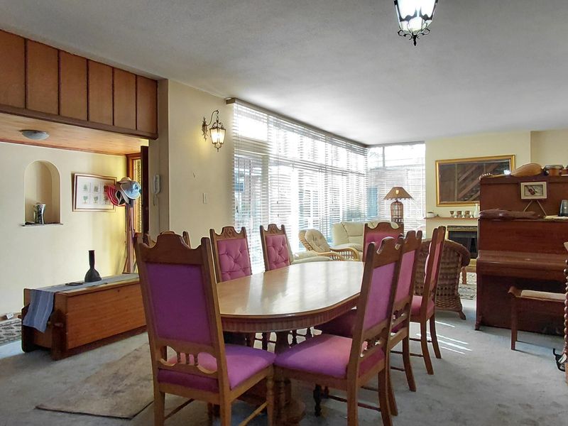 Spacious open-plan living and dining area featuring a fireplace, wood paneling details, and large windows providing ample natural light.