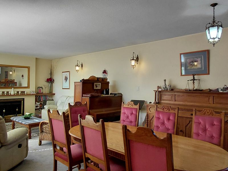 Spacious open-plan living and dining area featuring a fireplace, traditional wall sconces, and pendant lighting, offering a comfortable and functional layout.