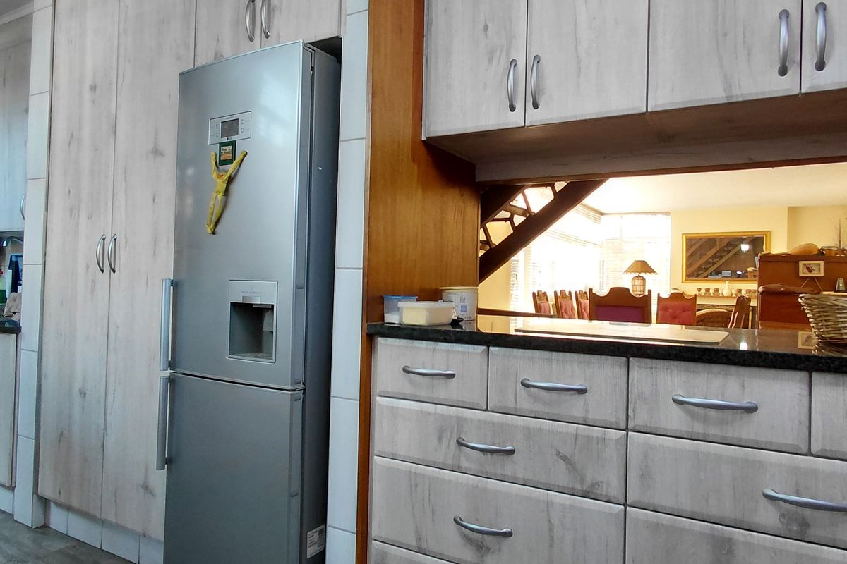 A functional kitchen featuring light wood-grain cabinetry, granite countertops, and a pass-through window overlooking the adjacent dining area.