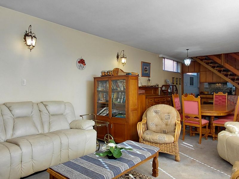 Open-plan living and dining area featuring a wooden staircase, neutral wall finishes, and wall-mounted lighting, offering a functional layout for family living.