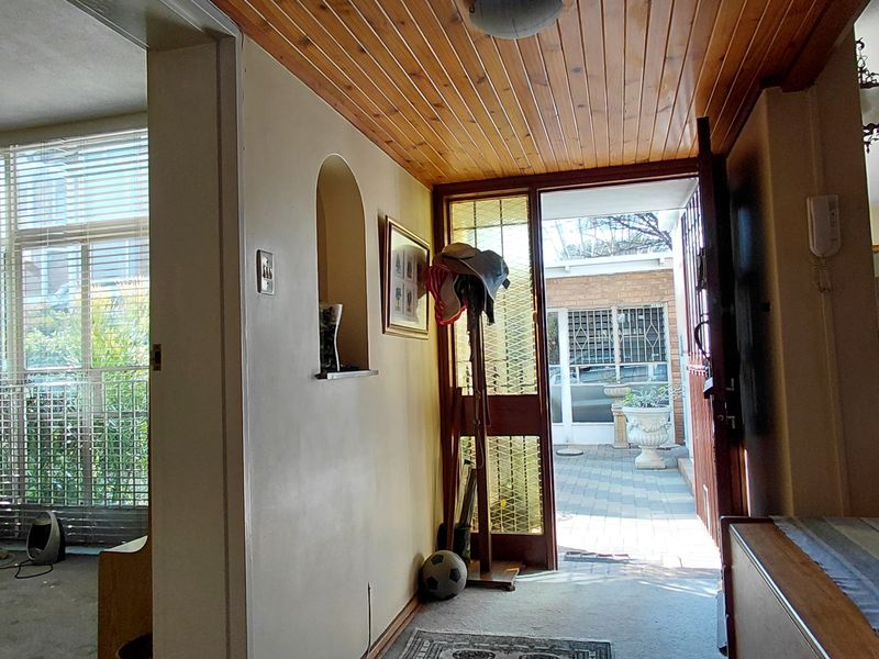 Entrance hall featuring a timber tongue and groove ceiling, leading into the main living area with views toward the exterior patio.
