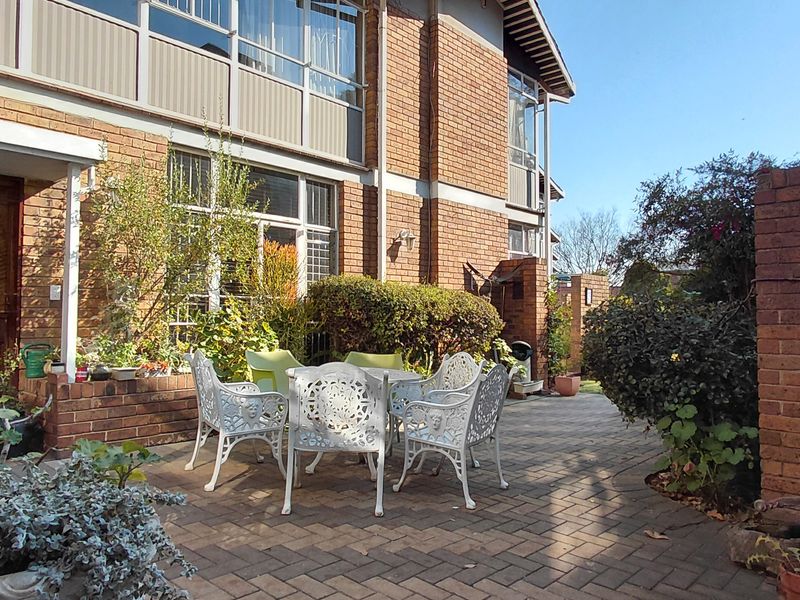 A private paved patio area featuring brick wall construction and direct access to the townhouse interior through sliding glass doors.