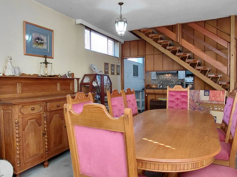 Open plan dining area featuring wood paneling, a wooden staircase, and natural light through horizontal blinds.