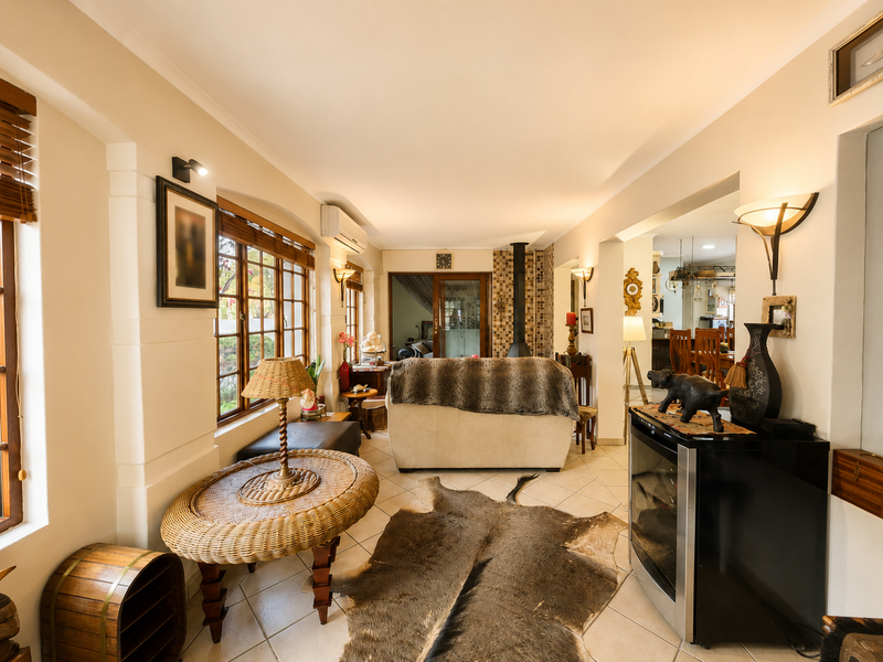 Spacious open-plan living area featuring tiled flooring, a central wood-burning fireplace, and large timber-framed windows providing ample natural light.
